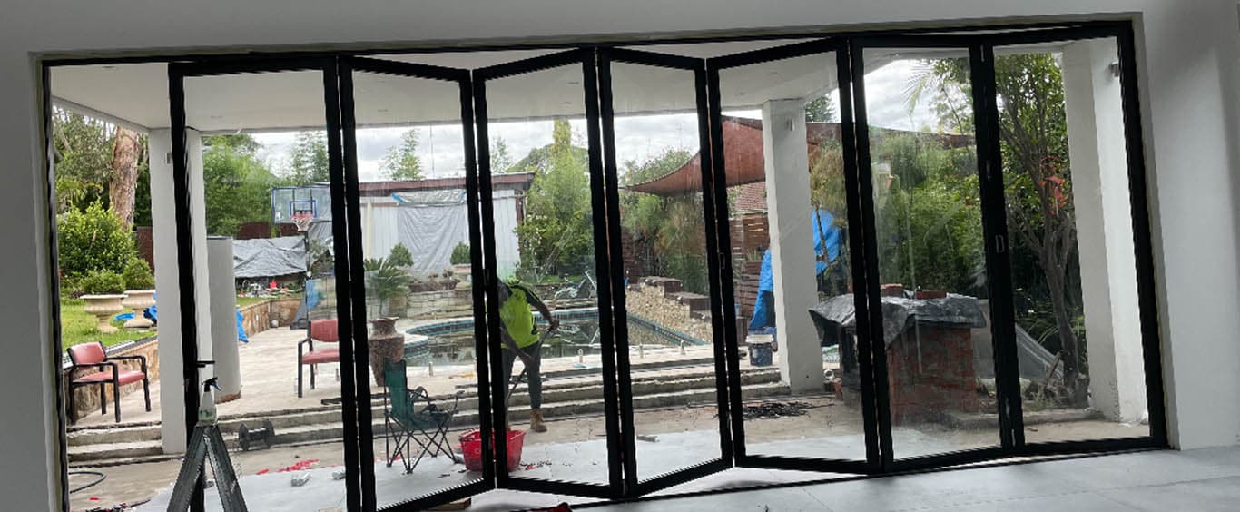 Black framed bifold stacker doors opening to backyard - DLT Renovations Sydney